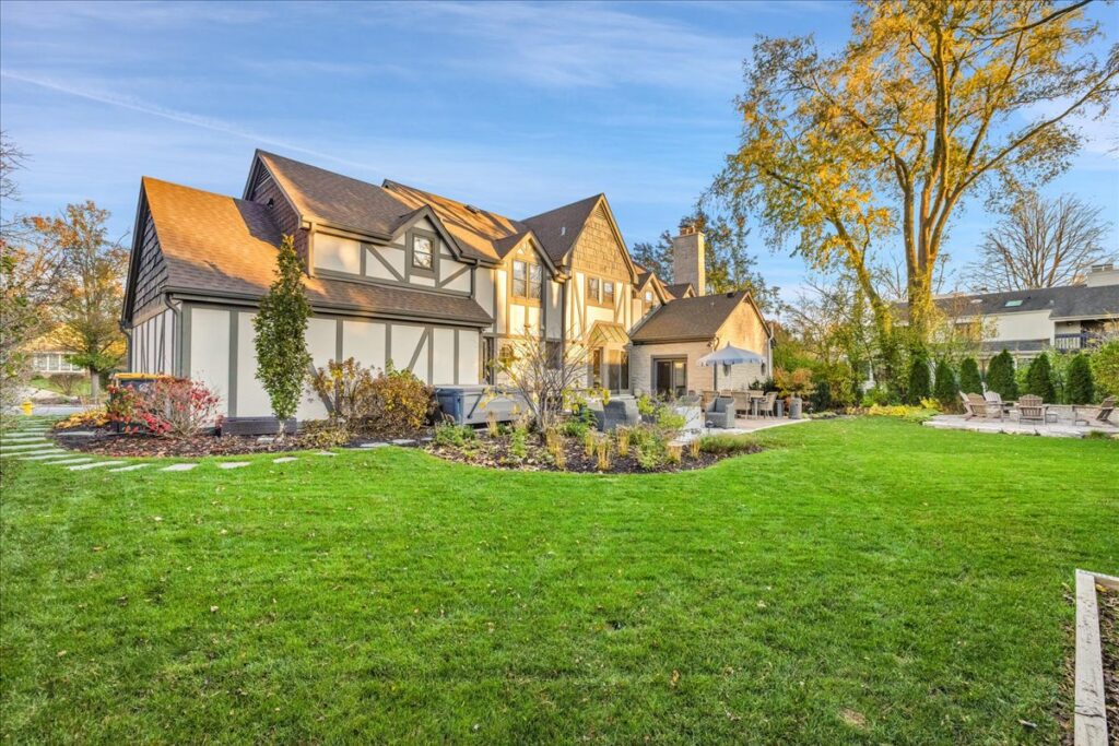 Rear exterior of a Tudor-style home with large lawn at golden hour